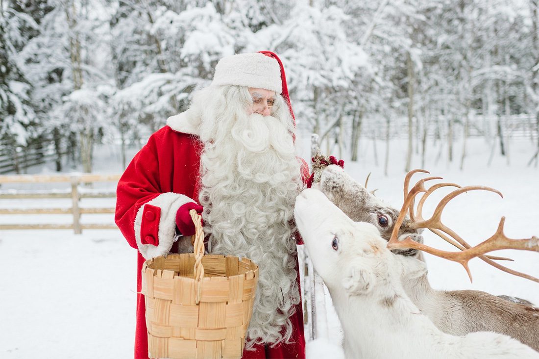 père noel qui caresse des rennes