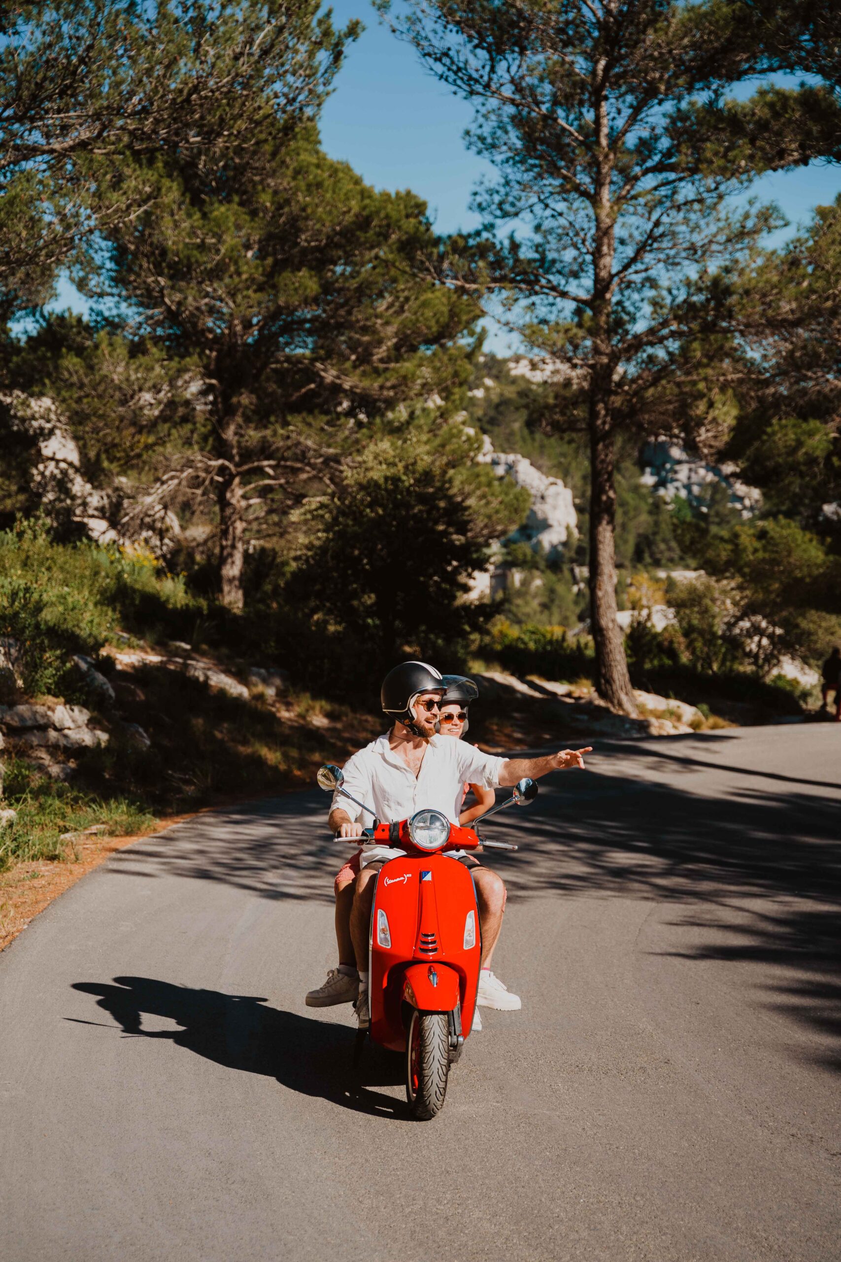 2 people driving an iconic red Vespa in Italy